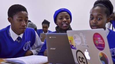 Two young men working on laptops in a green room.